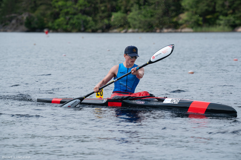 Person paddling a kayak on a lake with trees in the background
