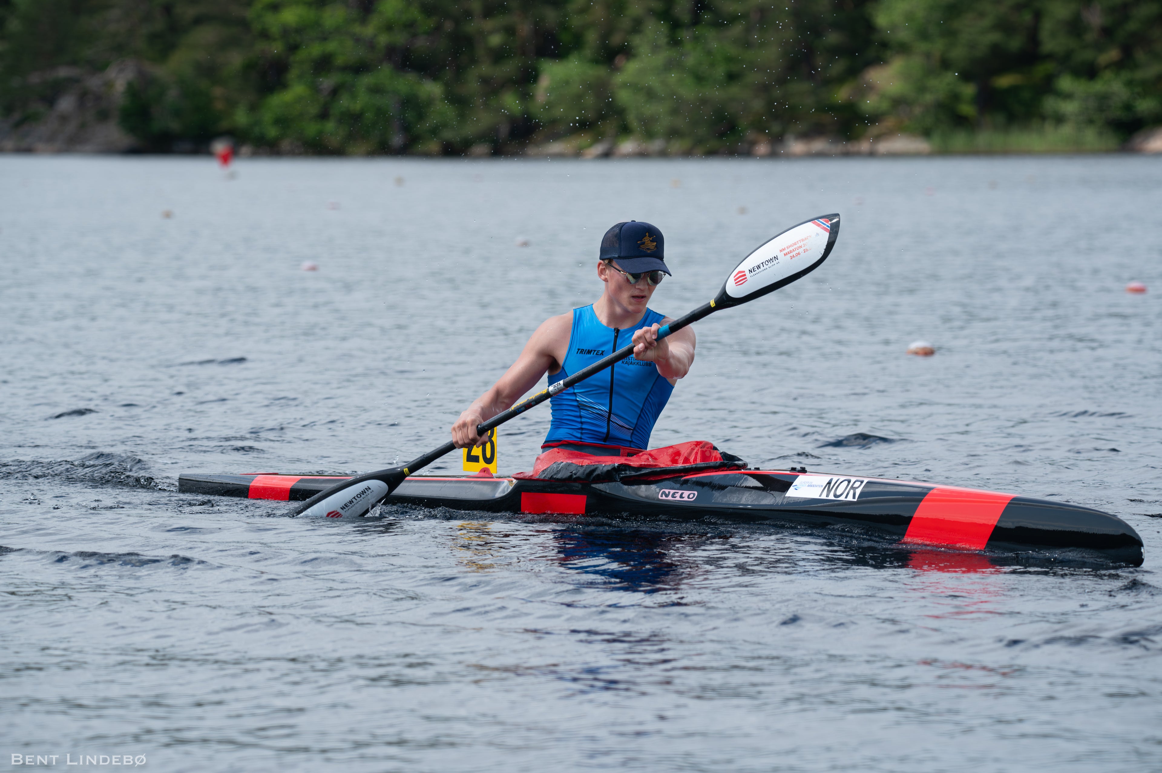 Person paddling a kayak on a lake with trees in the background